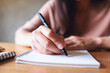 © Farknot Architect - Closeup image of a woman writing on notebook on wooden table