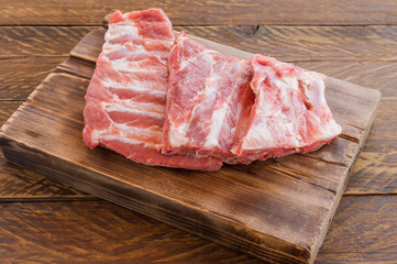 Pork ribs uncooked on wooden cutting board. Rusty style, close up