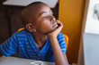 © WavebreakMediaMicro - Bored african american schoolboy sitting at desk looking out of window in classroom