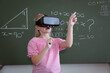 © WavebreakMediaMicro - Caucasian schoolgirl standing at chalkboard in classroom wearing vr headset