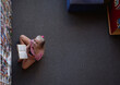 © WavebreakMediaMicro - Overhead view of smiling caucasian schoolgirl sitting on floor reading book in school library