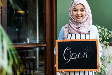 Poster - Muslim woman small business owner holding blackboard with smiling