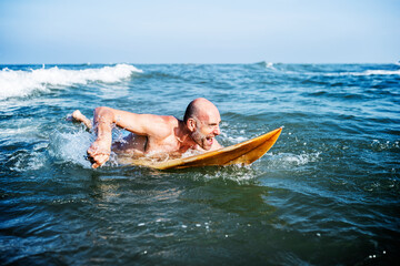 Wall Mural - A senior man on a surfboard