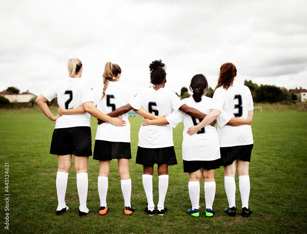 Female soccer players huddling and standing together - obrazy, fototapety, plakaty 