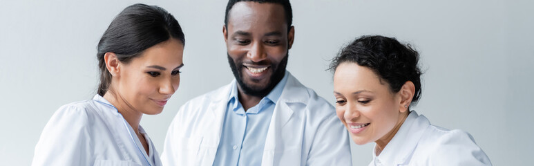 Wall Mural - Smiling interracial doctors looking down in clinic, banner