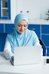 Wall Mural - Muslim scientist using laptop near digital tablet and petri dish