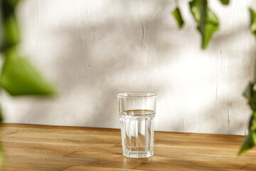 Wall Mural - Glass of water on desk and wall with shadows 