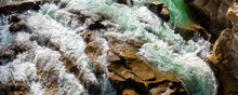 Close-up Abstract Texture Above View Of River Torrent And Clear Fresh Cold Water Flowing Through Mountain Rocks In Valley With Foam Bubbles On Sunny Day. Nature Force Power Background. Wide Banner