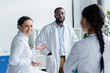 © LIGHTFIELD STUDIOS - African american doctor talking to colleague on blurred foreground in clinic