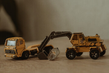 Poster - Closeup image of two black and yellow weathered construction machine toys on a wooden surface