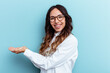 © Asier - Young mexican woman isolated on blue background holding a copy space on a palm.
