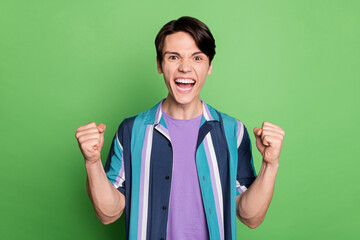 Sticker - Photo of hooray brunet young guy hands fists yell wear striped shirt isolated on green color background