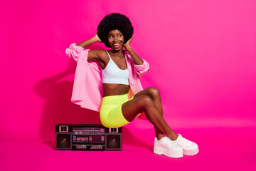 Photo of impressed cute dark skin lady wear casual shirt sitting boom box looking empty space isolated pink color background