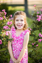 Young Girl In Pink Dress Laughing As She Stands Outside In Garden