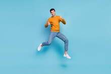 Photo Of Funky Cute Young Man Wear Yellow Sweater Smiling Jumping High Showing Thumbs Up Isolated Blue Color Background