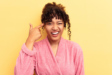 Wall Mural - Young mixed race woman wearing a pink bathrobe isolated on pink background showing a disappointment gesture with forefinger.