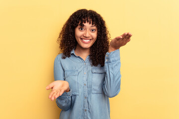 Wall Mural - Young mixed race woman isolated on yellow background makes scale with arms, feels happy and confident.