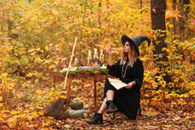 Young Witch Writing Spells In Forest