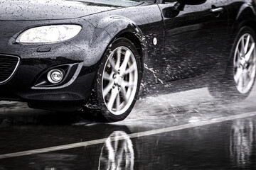 Sticker - Sports car driven on rainy roads close up on a wheel with motion blur effect