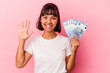 © Asier - Young mixed race woman holding bills isolated on pink background smiling cheerful showing number five with fingers.