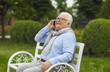 © Studio Romantic - Happy senior citizen talking on his mobile phone. Cheerful active white haired old man making a call on his cellphone while sitting on a park bench against the background of summer greenery