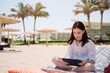 © D'Action Images - Cut teenager girl using tablet on the background of the beach. Summer vacation concept, studying online with tablet, distance learning, self education, beach work