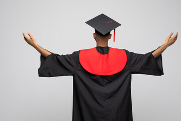 Wall Mural - happy smiling indian male graduate student in mortar board and bachelor gown with diploma celebrating success over grey background