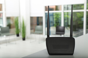 Modern Wi-Fi router on grey table indoors, space for text