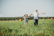 The girl sits on the shoulders of her grandfather while walking in the field. Happy vacation concept with grandparent