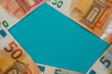 Wall Mural - Top view of five and fifty euro banknotes forming a pentagon on a blue background