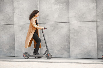 Wall Mural - Positive smiling woman riding a kick scooter