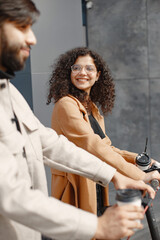 Wall Mural - Interracial young couple with scooters in the city background