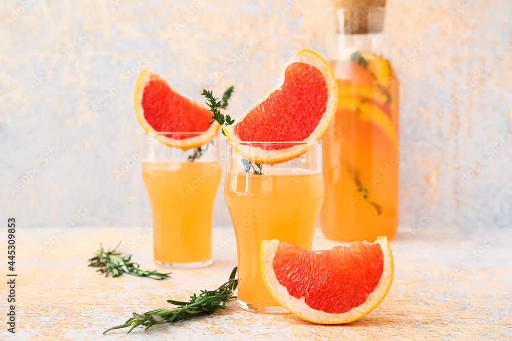 Glasses of tasty grapefruit juice on light background