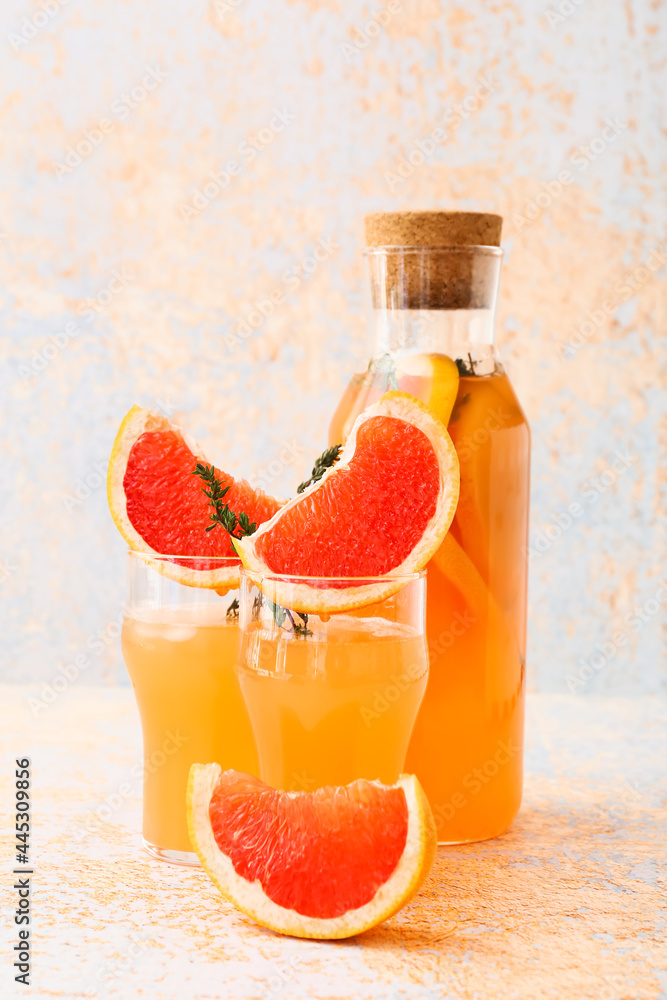 Glasses of tasty grapefruit juice on light background