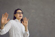 © Studio Romantic - Yuck. Scared woman with expression of fear, fright and disgust on face asking you to stop. Young lady on grey studio background afraid of something dangerous or repulsive doing protective hand gesture