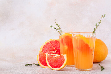 Glasses of tasty grapefruit juice on light background