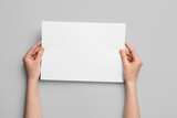 Fototapeta Mapy - Woman holding blank sheet of paper on grey background