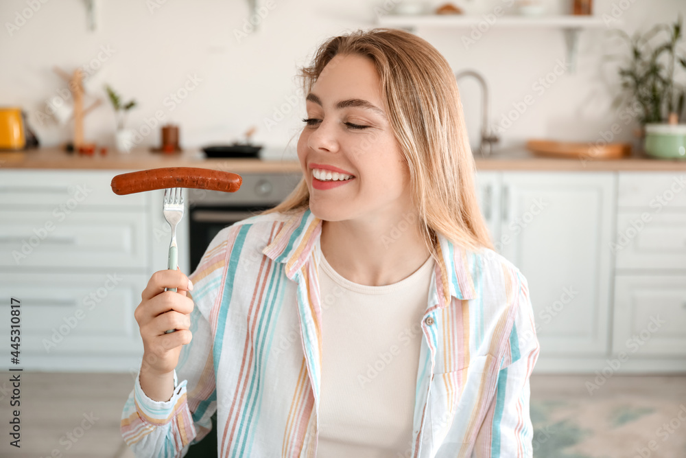 Young woman with tasty sausage in kitchen