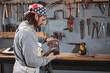 © astrosystem - Male carpenter working on old wood in a retro vintage workshop.
