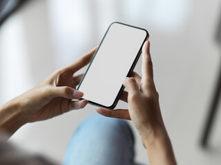 Top view of female hands using mobile phone with blank screen