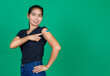 © Bangkok Click Studio - Middle aged Asian woman smiling showing her arm with bandage patch showing she got vaccinated for Covid 19 virus on green background. Concept for Covid 19 vaccination