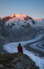 Fototapete - A woman looking over the Gorner glacier at the mountains during sunset.
