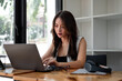 © Natee Meepian - Asian woman using laptop computer with headset at home, Online learning education concept