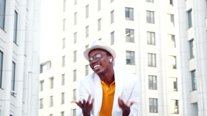 Wall Mural - Smiling black guy in t shirt and suit dances on street