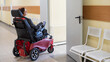 Caucasian woman in electric wheelchair in hospital corridor.