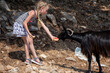 © Nataliia Makarovska - happy little girl feeding watermelon to wild goat on a sunny day, horizontal