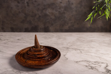 Closeup of a wooden incense burner on the white marble surface.