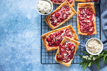 Wall Mural - Top view of puff pastry mini pies with cream cheese and strawberry decorated with almond.