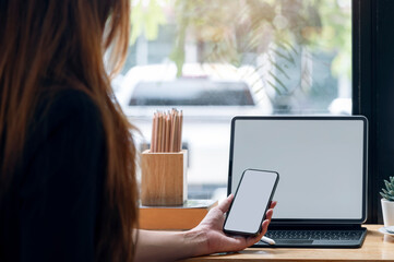 Wall Mural - cropped shot of woman hand holding blank screen smartphone while sitting at couonter table in cafe.