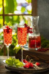 Wall Mural - Two glasses of fresh cold currant cocktail on the table near the window, sunny backlight